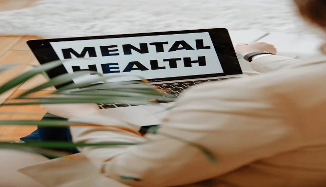 A lady in front of her laptop with written words “MENTAL HEALTH”