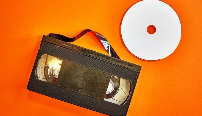 An image of a video tape and disc on an orange background.