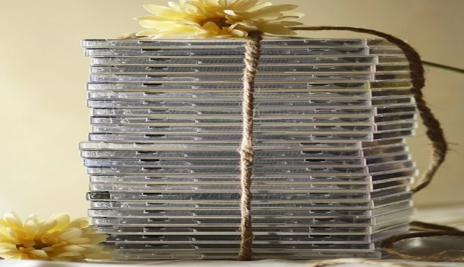 A tied-up stack of CDs with two yellow flowers.